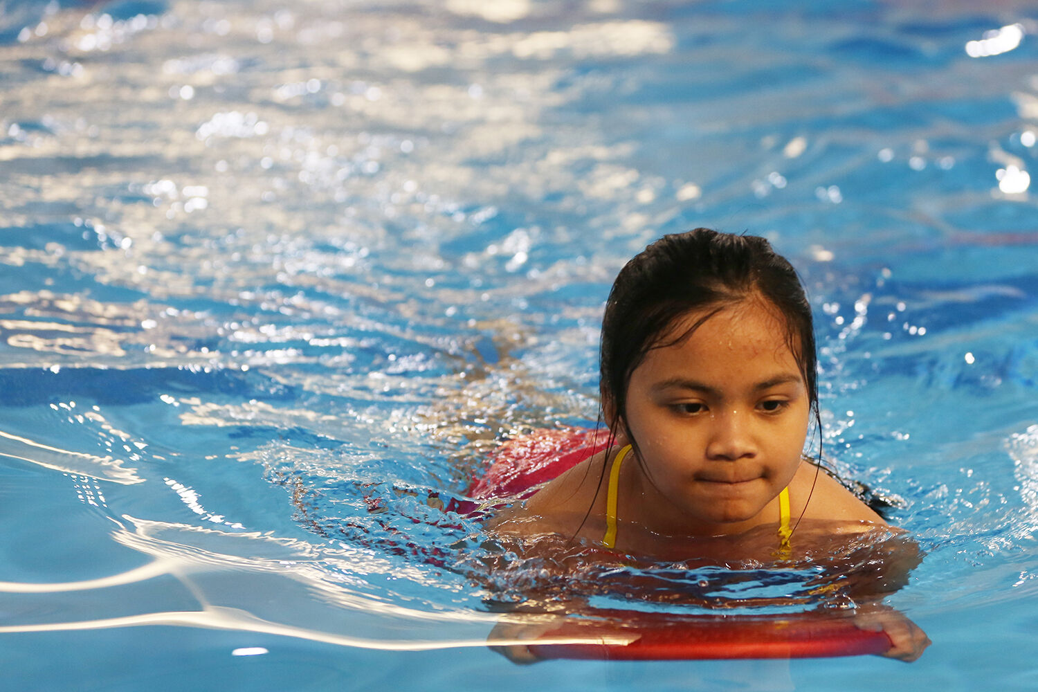 Bianca Soliven, 10, uses her kick board to kick her way across the pool